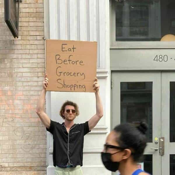 dude with a sign Eat Before Grocery Shopping
