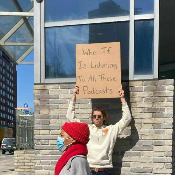 dude with a sign Who , Tf Is Listening To All These 2 Podcasts