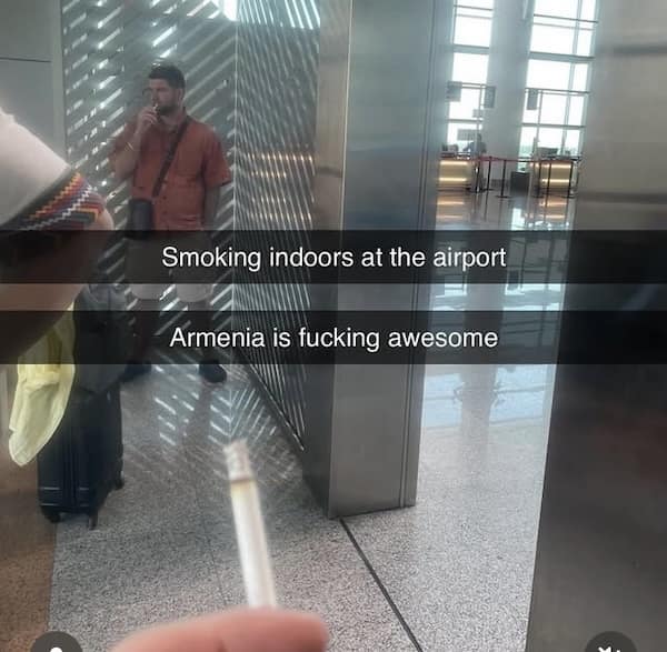Man smoking at an airport with caption “Smoking indoors at the airport—Armenia is awesome”