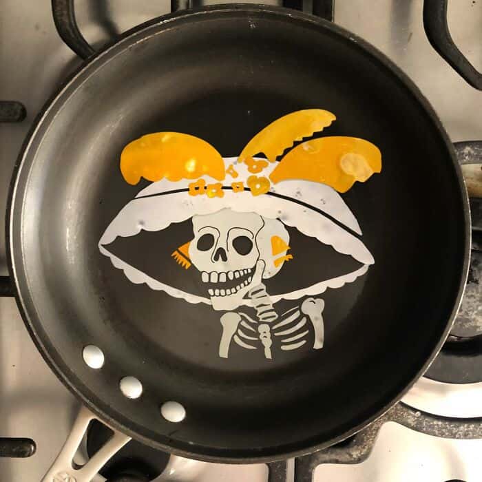 Fried egg art of a skeleton wearing a large decorative hat