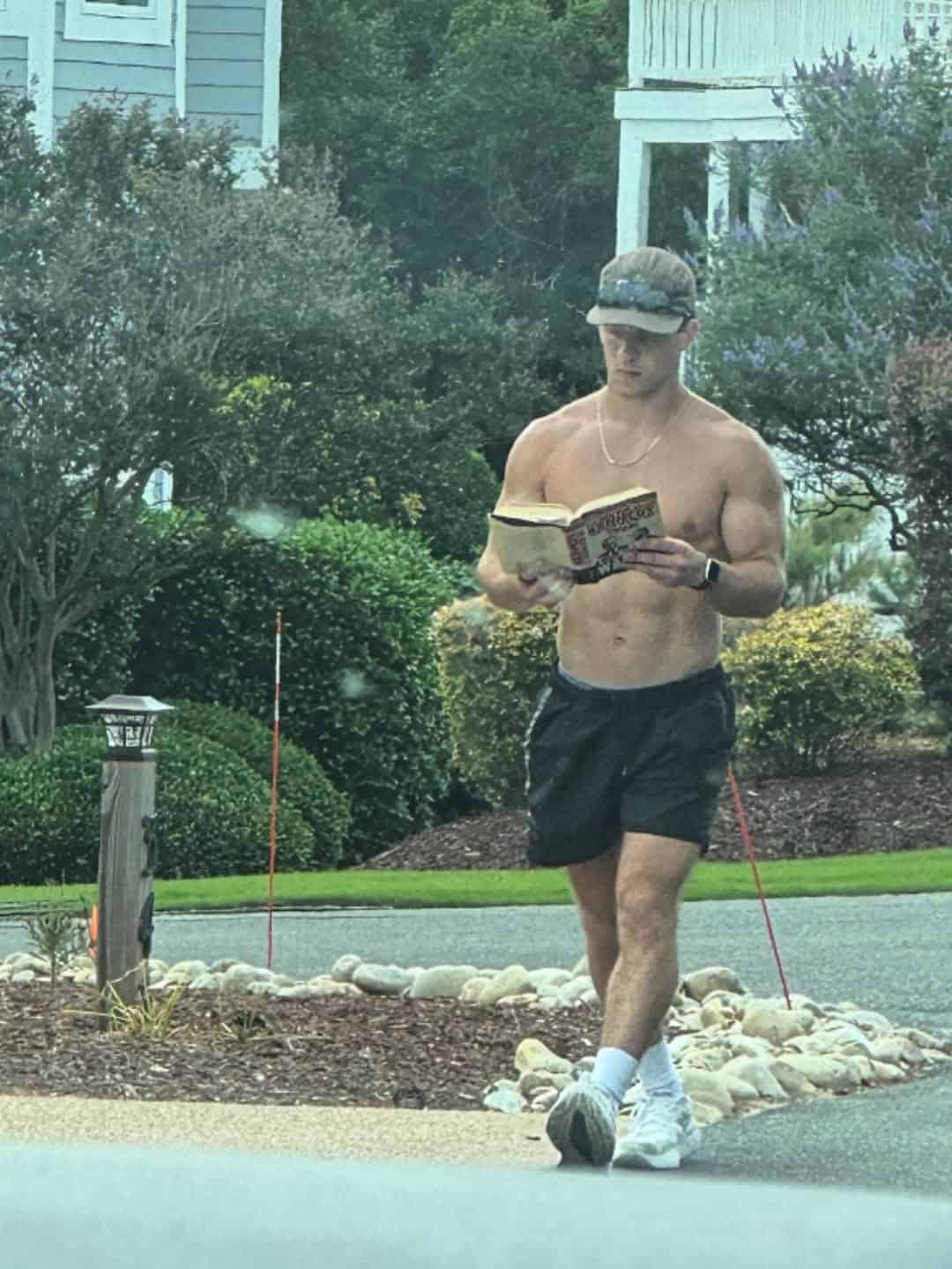 Shirtless man reading a book while walking outside