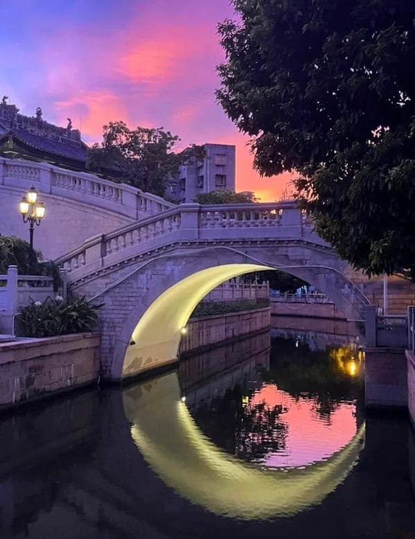 Bridge reflection forming a glowing semicircle at dusk