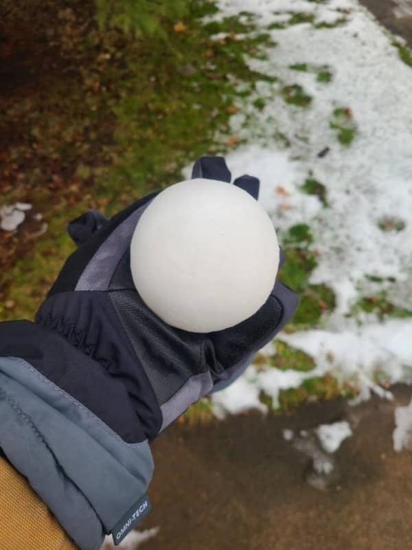 Satisfying photo of a flawless, perfectly spherical snowball held in a gloved hand, showcasing the oddly soothing perfection found in nature.