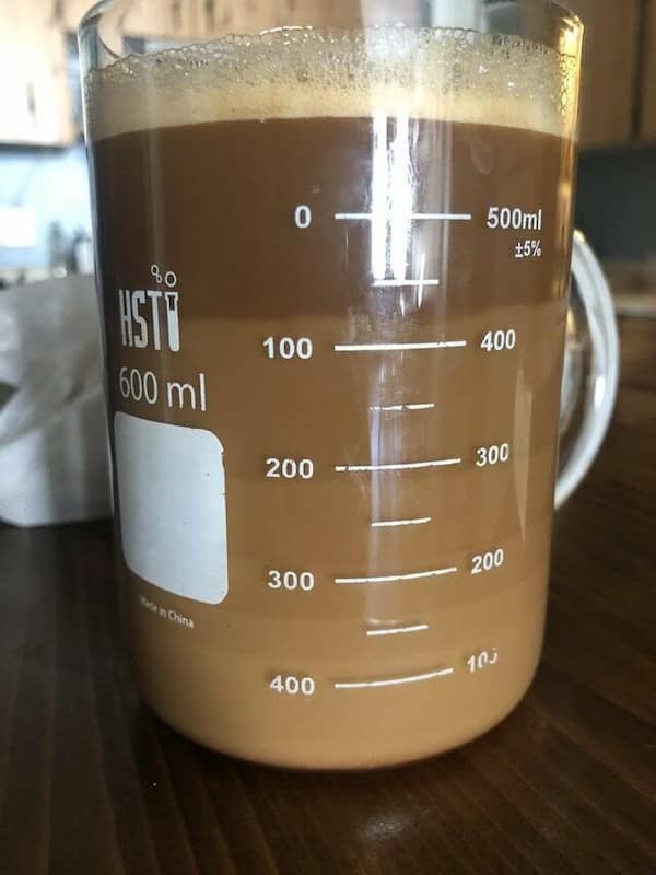Satisfying photo of a laboratory beaker precisely filled to the 600ml mark with creamy coffee, the foam resting evenly on top for extra visual appeal.