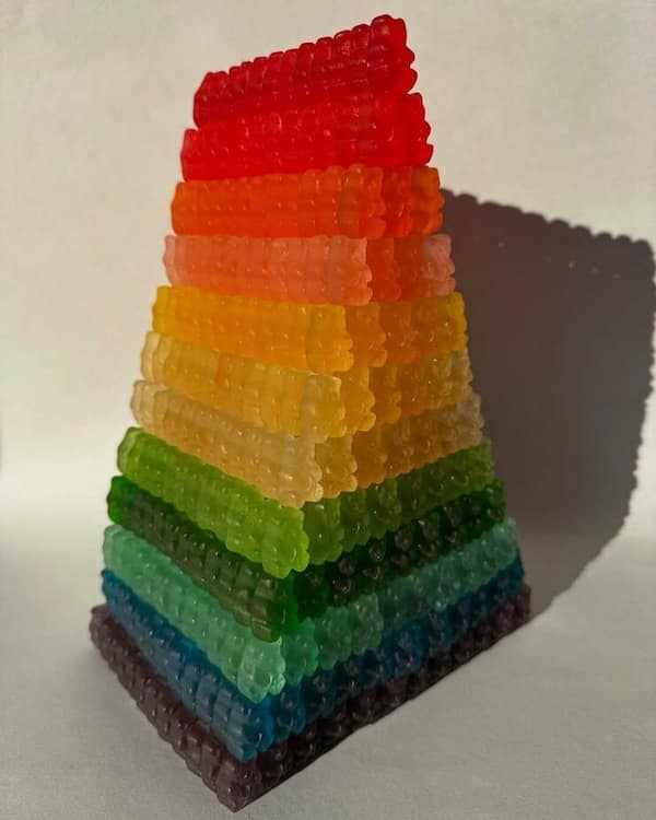 Satisfying photo featuring a pyramid made of gummy bears, with each layer neatly stacked by color, creating a cheerful and organized rainbow effect.