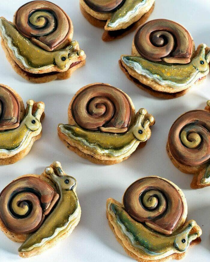 Hand-painted snail-shaped sandwich cookies with swirled shells.