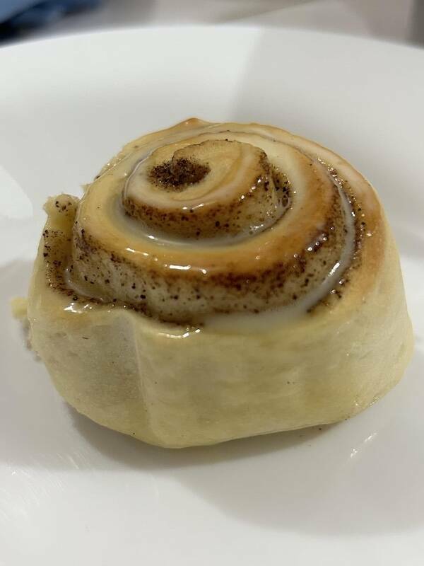 Close-up of a glazed cinnamon roll spiral on a white plate