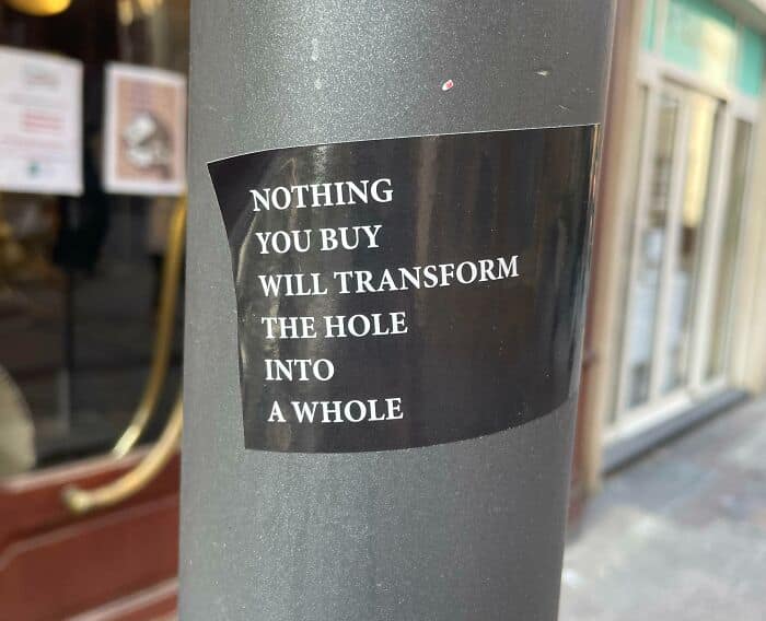 A powerful anti consumption meme on a sticker with a message about consumerism.