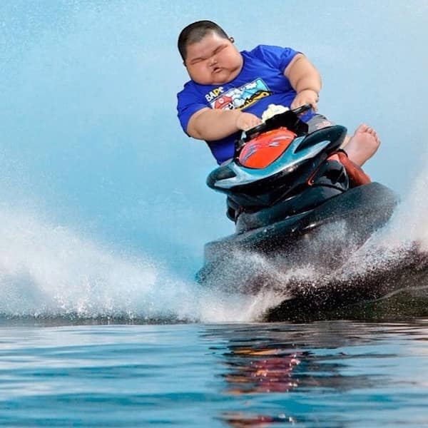 A funny photoshop of a young boy with a disproportionately large head riding a jet ski.