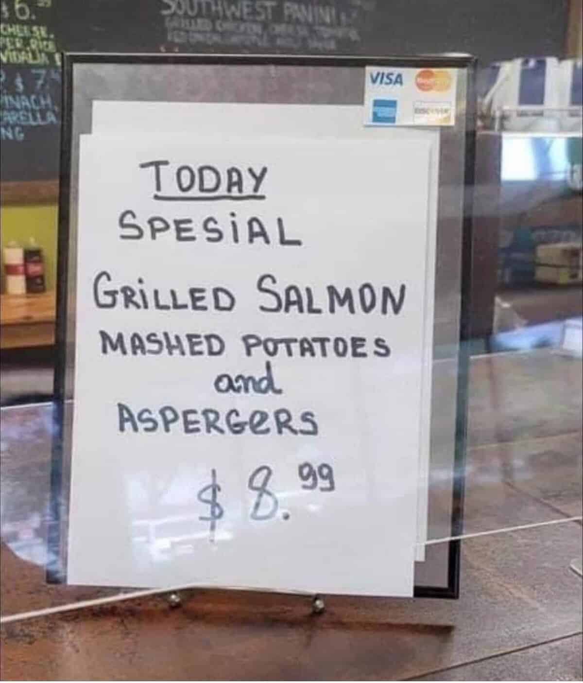 Handwritten sign at a deli reads “Today Spesial: Grilled Salmon, Mashed Potatoes and Aspergers – $8.99.”