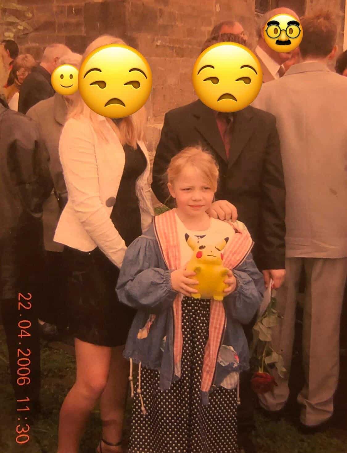 Little girl at a formal event holding a Pikachu toy, polka-dot dress and denim jacket, adults’ faces covered with emojis.