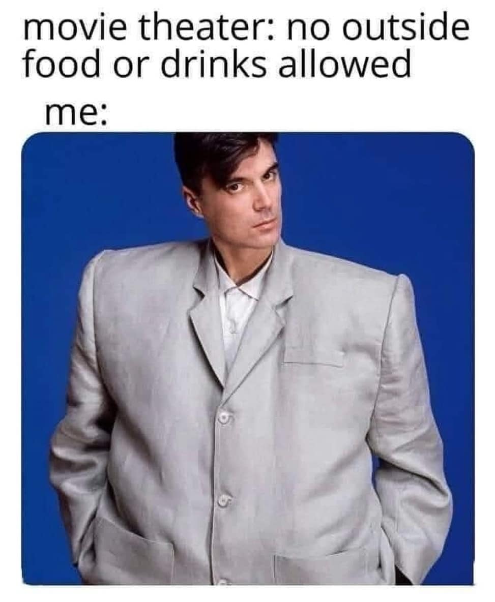 Man in comically oversized gray suit (big shoulders) used as joke for sneaking food into a theater.