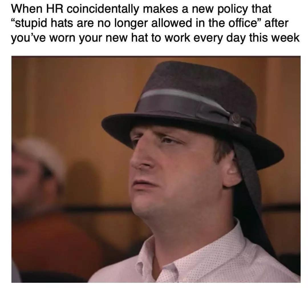 A man in a fedora looks offended, with text about HR banning "stupid hats" right after he’s been wearing one all week.