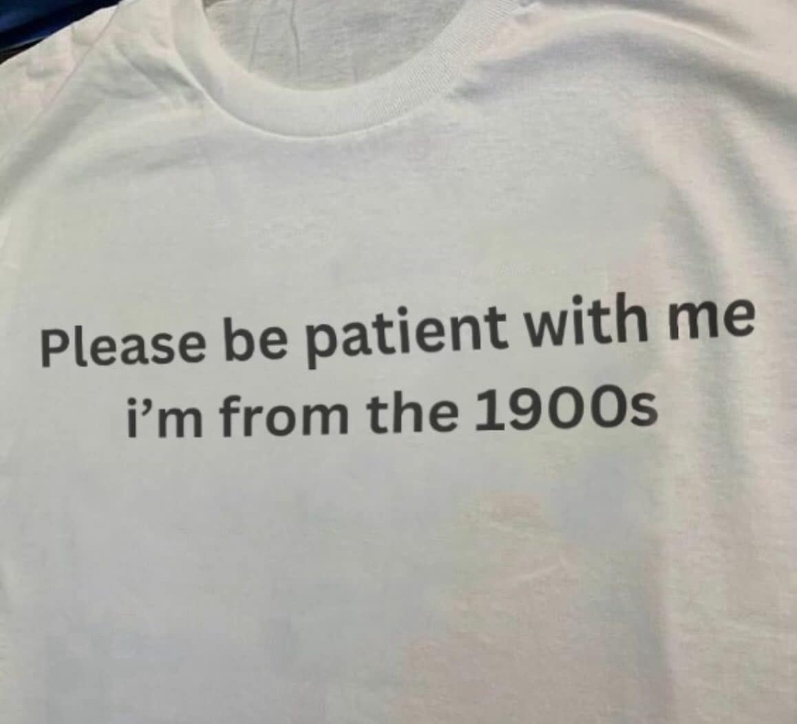 White T-shirt printed with “Please be patient with me I’m from the 1900s.”