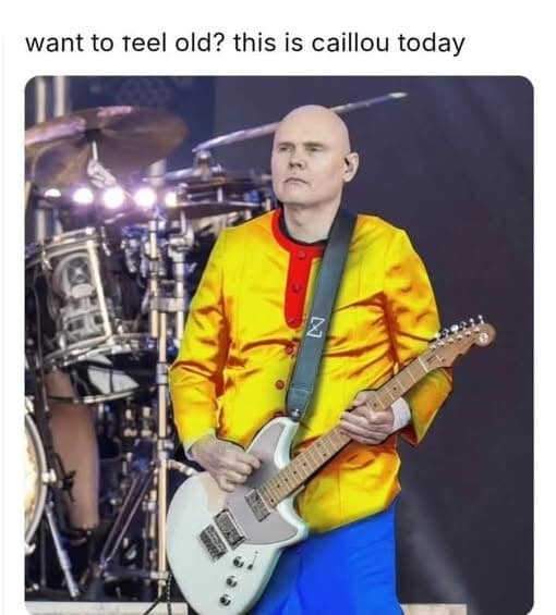 Bald guitarist onstage wearing a bright, Caillou-style outfit.