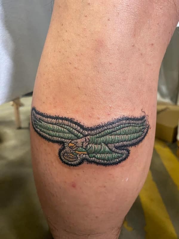 Green eagle in flight rendered with dense thread-like lines and a fuzzy stitched border on a calf.