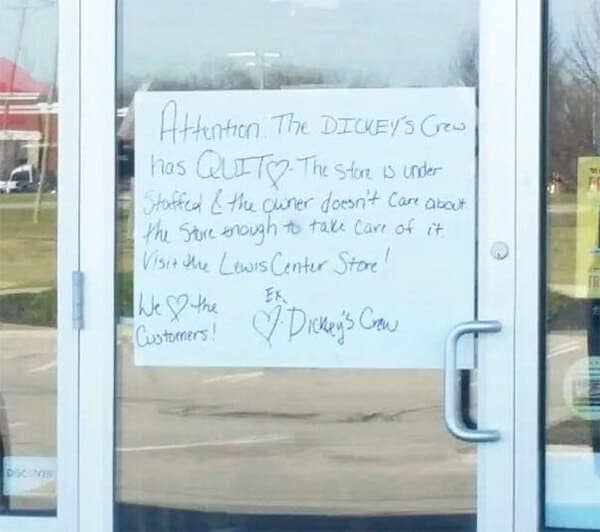 Storefront with a handwritten sign stating the entire Dickey’s crew has quit due to understaffing and lack of care from ownership.