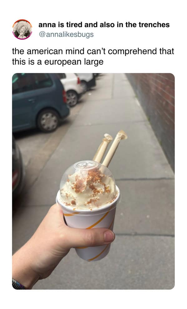 Hand holding a small sundae with two sticks and whipped cream.