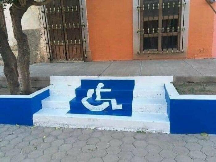 A wheelchair accessibility symbol painted directly onto a set of stairs instead of a ramp.