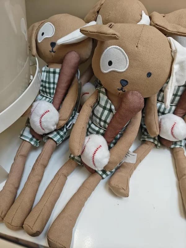 A funny meme showing a poorly designed stuffed dog toy holding a baseball bat.