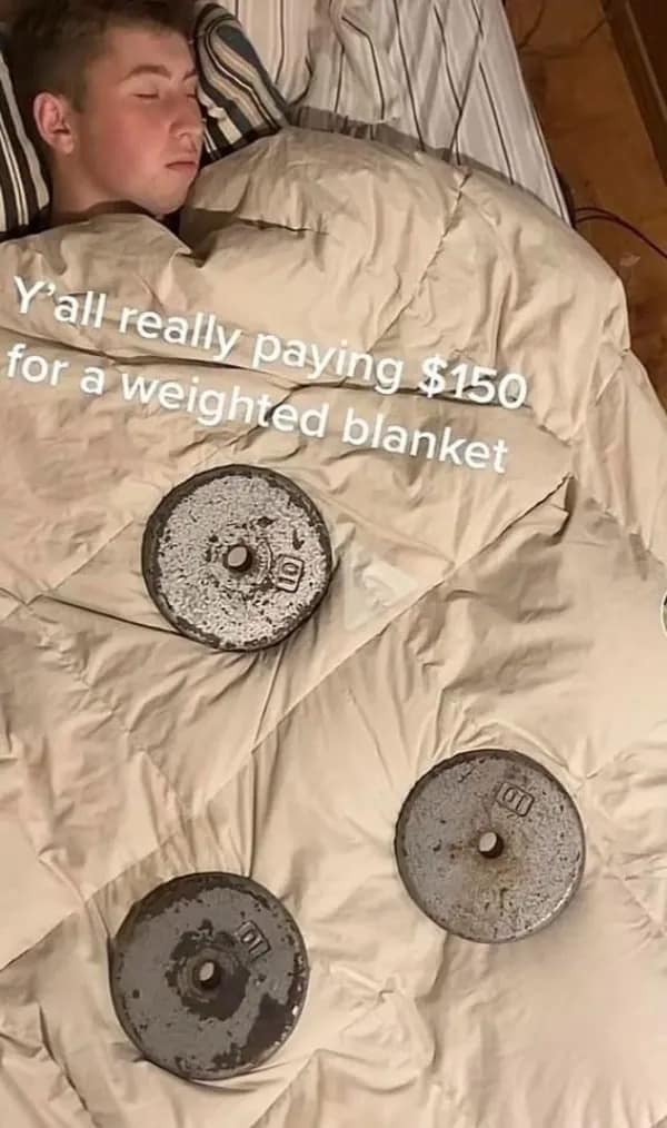 A person sleeping with heavy barbell plates on their comforter as a makeshift weighted blanket.