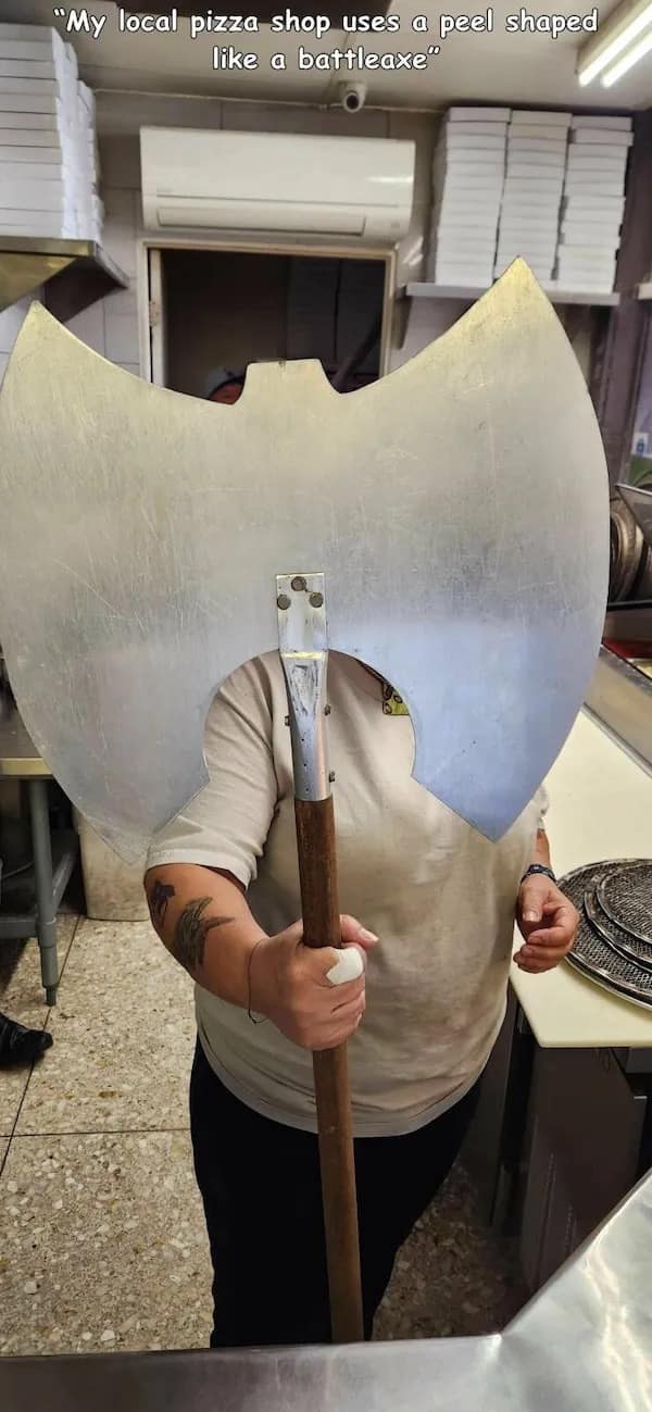 A funny meme of a pizza shop worker holding a giant pizza peel shaped like a battleaxe.