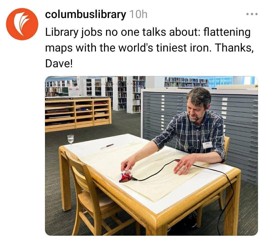 A funny pic from the Columbus Library showing a librarian using a tiny iron to flatten maps.