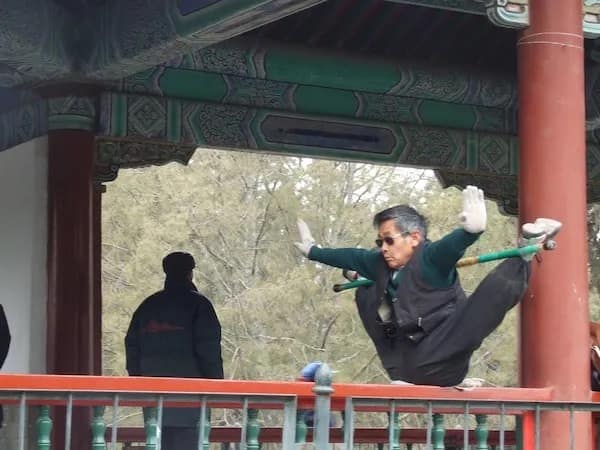 A funny pic of an older man doing an impressive and painful-looking split on a railing.