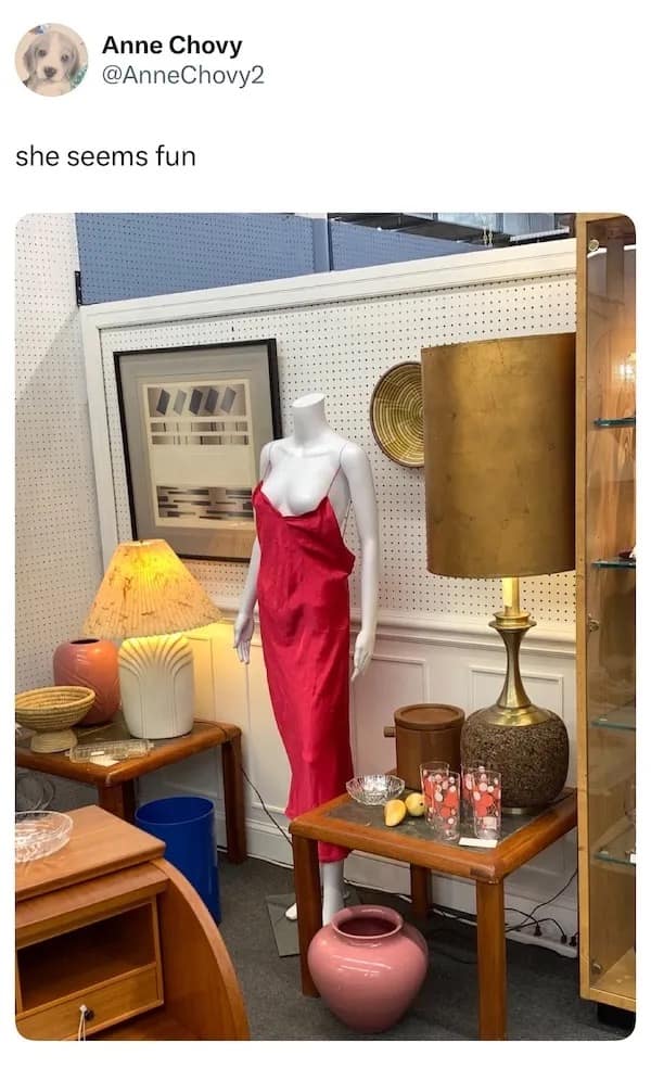 A funny picture of a mannequin in a vintage store with her red dress falling off.