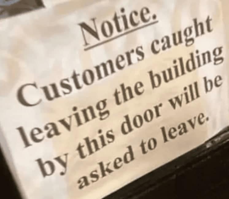 Notice says customers leaving by this door will be asked to leave.