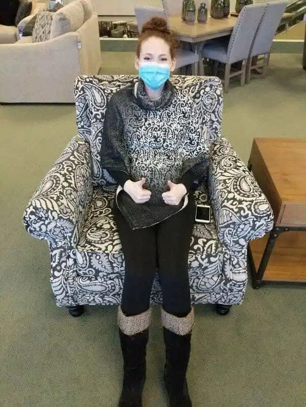 Woman in ornate poncho sitting on an armchair with the same pattern.