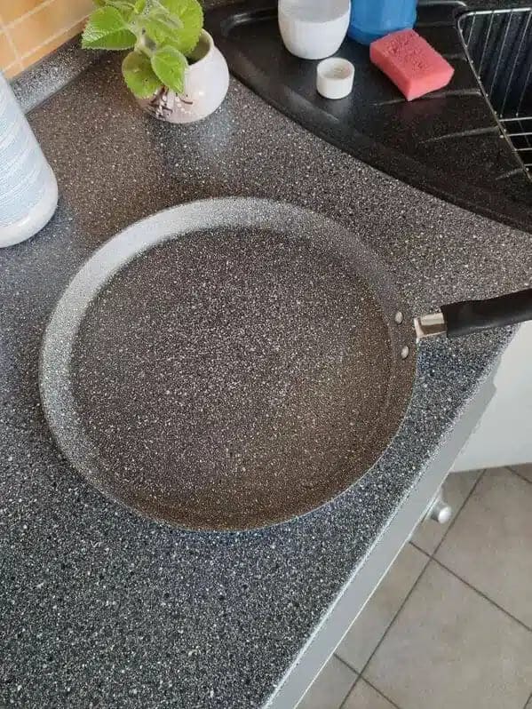 Speckled frying pan on a speckled countertop, edges barely visible.