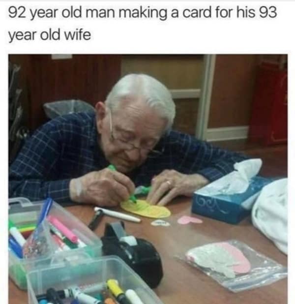 Elderly man crafting a card for his wife with colorful paper and markers