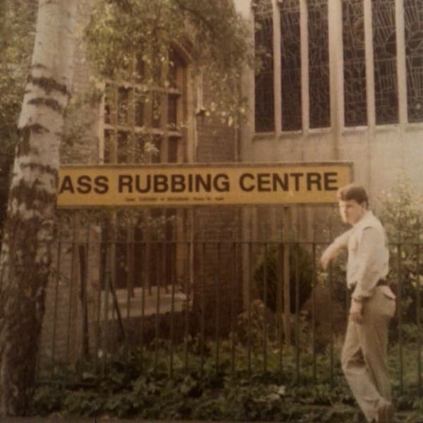 Vintage sign appears to read “ASS RUBBING CENTRE” from a cropped “Brass Rubbing Centre” outside a church.