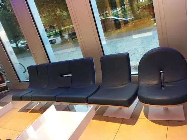 Row of modern waiting-room chairs, one chair back oddly shaped like a toilet seat.
