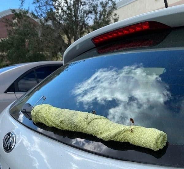 A hilarious redneck engineering car fix using a towel and safety pins as a windshield wiper.
