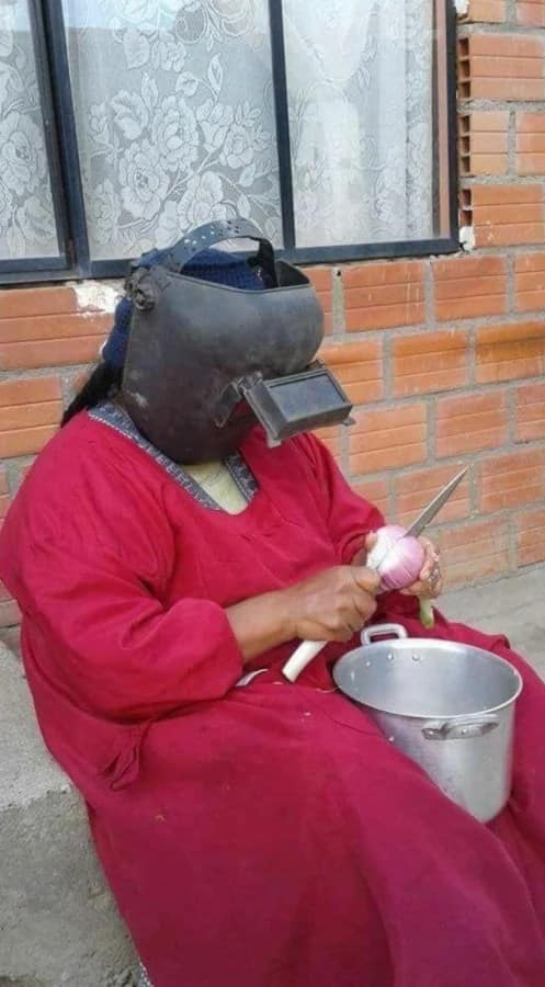 Woman peeling onions while wearing a welding helmet, demonstrating peak redneck ingenuity