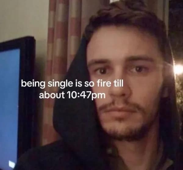 Hoodie selfie with tired face, caption “being single is fire until 10:47 pm” relatable meme.