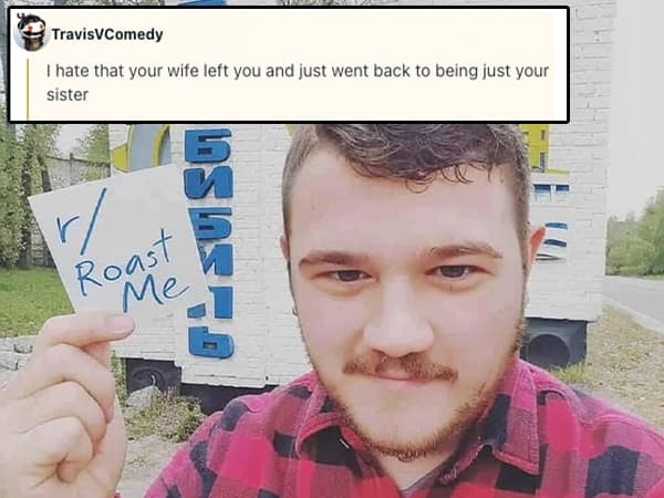 Bearded man in a flannel shirt holding a “r/Roast Me” sign outside in front of a blue sign with Cyrillic letters
