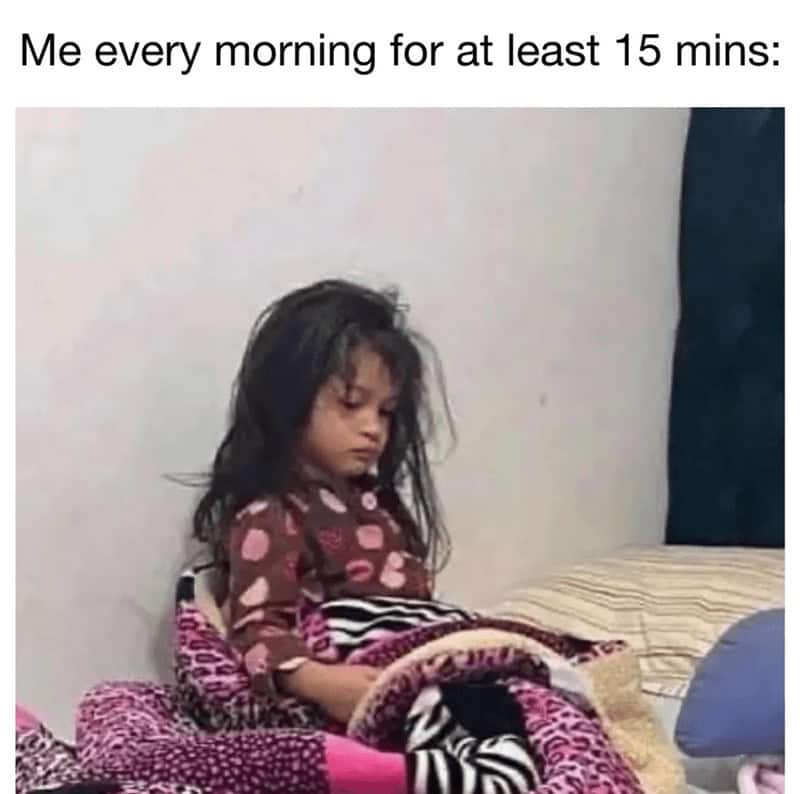 A sleepy meme of a very tired young girl sitting in bed, struggling to wake up in the morning.