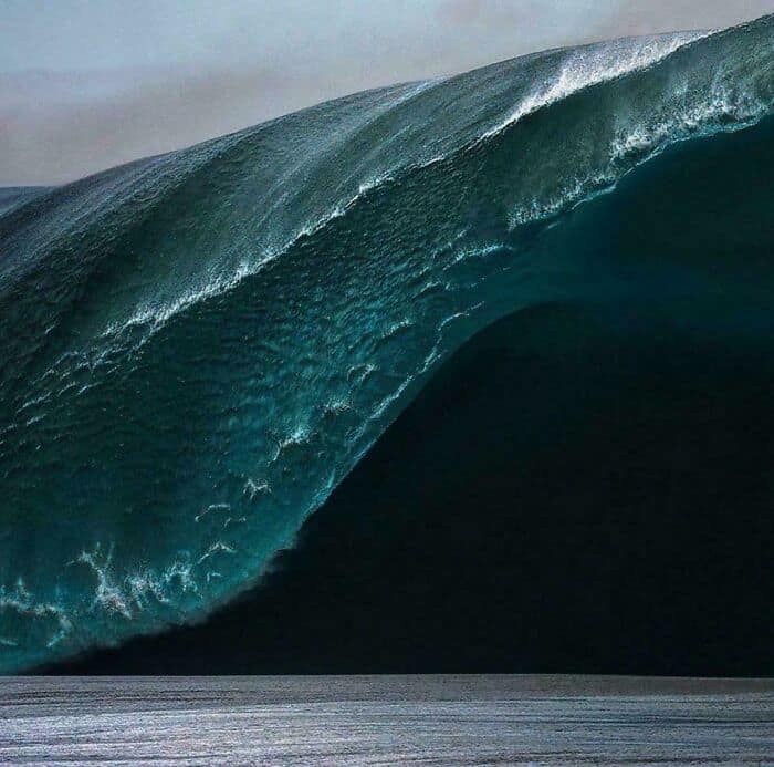 A massive, dark blue wave cresting with white foam, showing the terrifying power of the ocean.