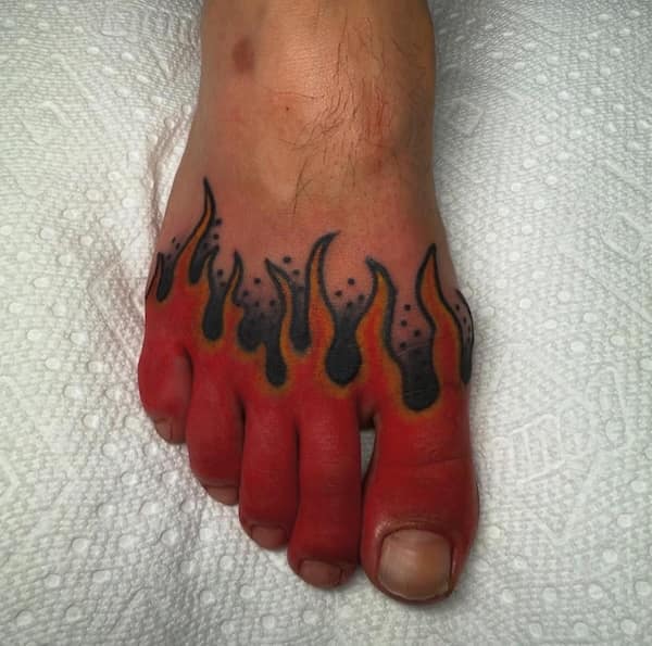 A foot tattoo designed with red and black flames across the toes.