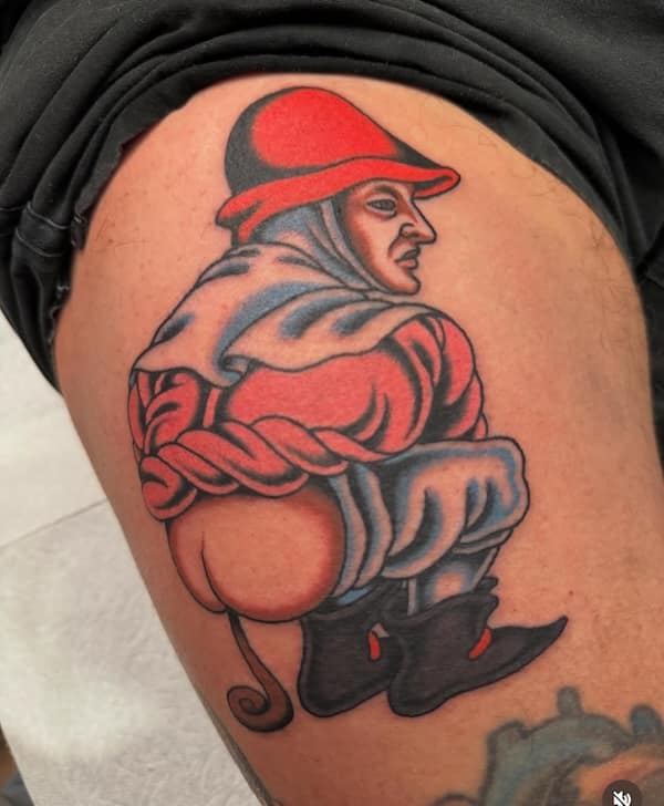 A tattoo of a medieval-style man squatting with his bare buttocks showing.