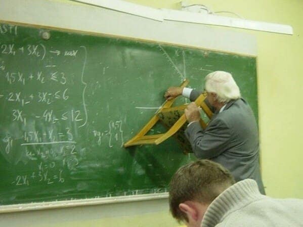 A funny picture of an old-school teacher using a folding chair as a ruler on the chalkboard.
