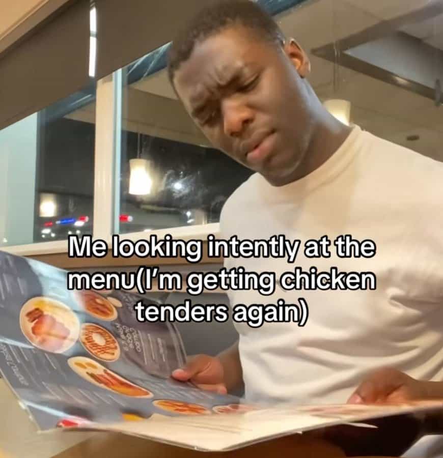 Man studying menu seriously at restaurant, pretending to decide