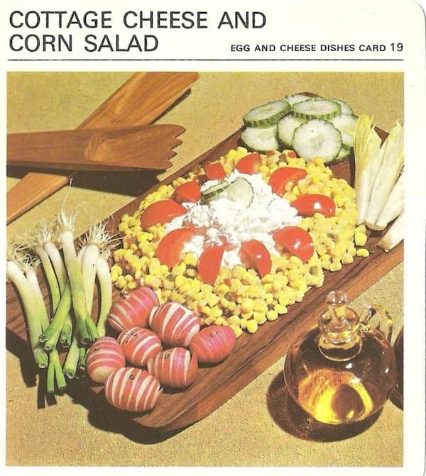 A retro recipe showing "Cottage Cheese and Corn Salad" on a wooden serving board.