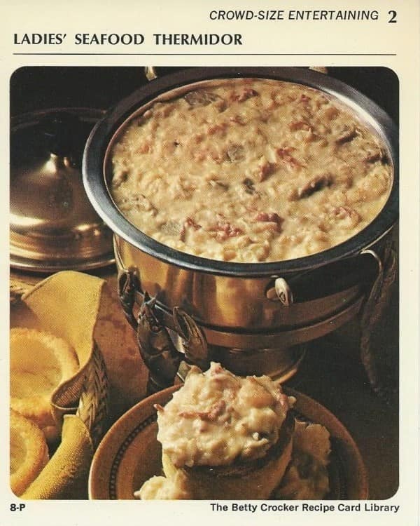 A Betty Crocker recipe for "Ladies' Seafood Thermidor" in a large silver chafing dish.