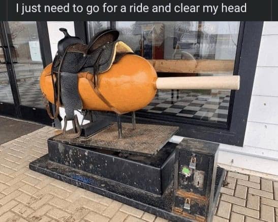 A funny mechanical ride outside a store that is shaped like a giant corn dog with a saddle.