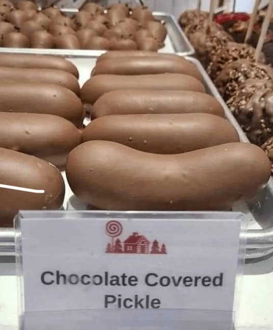 A photo of a tray of large, chocolate-covered pickles for sale at a sweet shop.