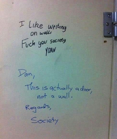 A funny and conversational graffiti exchange where "Society" politely corrects a person's angry graffiti, pointing out that they have actually written on a door, not a wall.